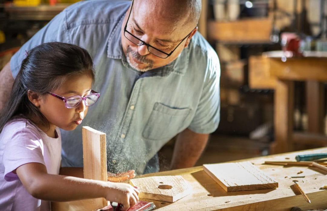 a Father building a bird house with his daughter