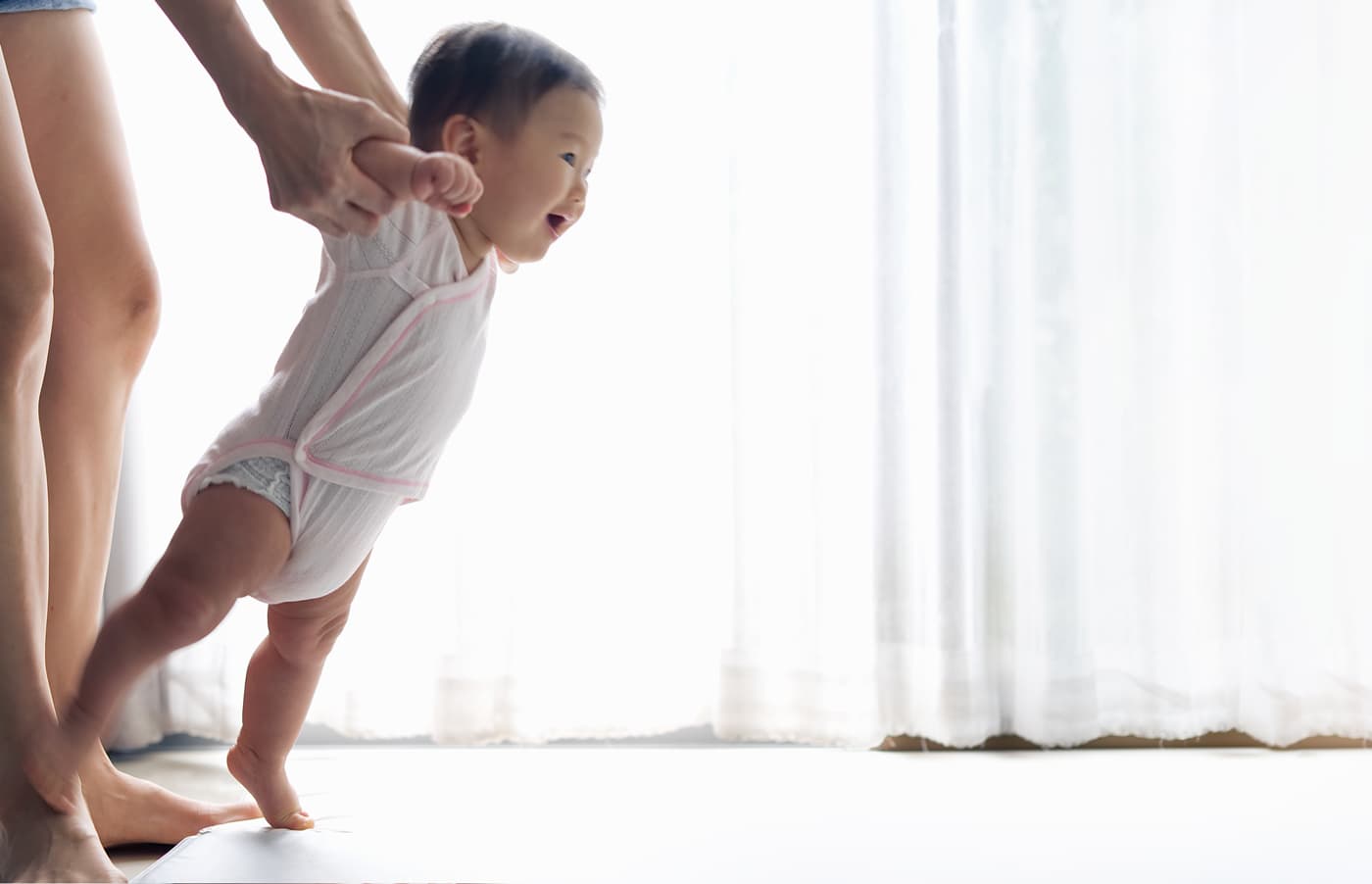 Mom holding an infant teaching them to walk